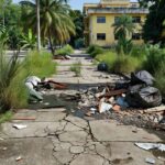 Calçada com mato e entulho em frente ao Colégio 21 de Abril